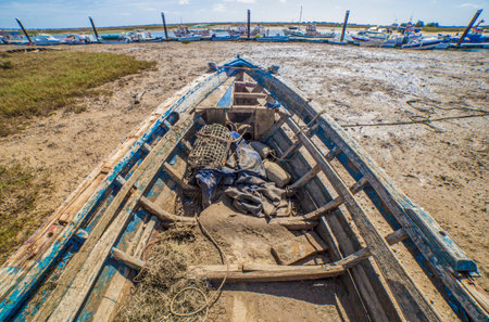 Old wooden fishing boat docked in low tide sand. Cabins of Tavira, Portugalの写真素材