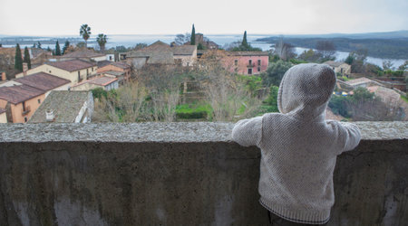 Grenadilla village. Hooded child boy enjoying an aerial view from castle. Extremadura, Caceres, Spainの写真素材