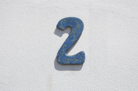 House number 2. Painted iron over whitewashed wall. Houses with personality concept