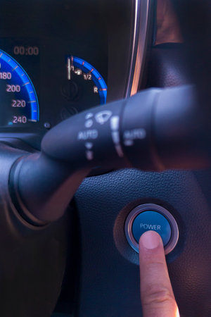 Finger pressing the car start button. Eco driving concept