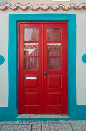 Tiny door painted with vivid colors at Vila Nova de Milfontes house. Little picturesque town on the Alentejo coast, Portugalの写真素材