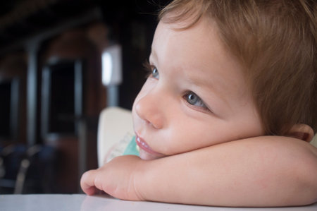 Pensive 2 years-old boy. He rests his head on his arm looking to the leftの写真素材