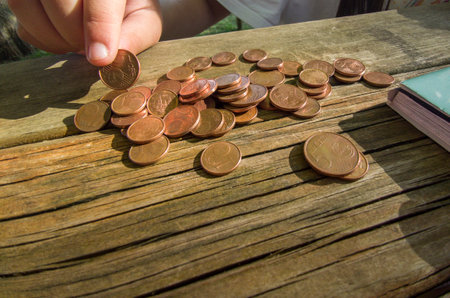 Little girl counting her pocket change savings. Weathered picnic table as backgroundの写真素材