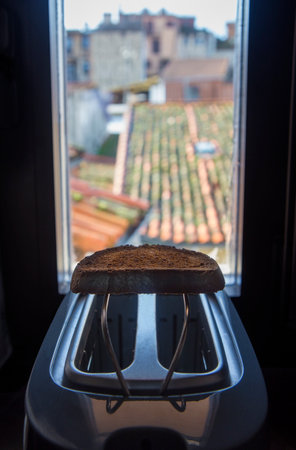 Toaster placed on the windowsill of a rural house. Fresh made slice over rack