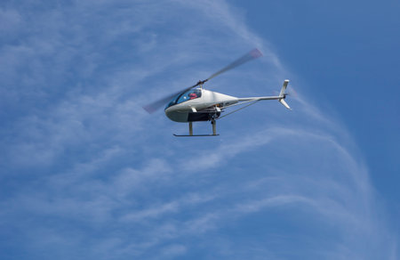 Ultralight kit-built helicopter flying over blue cloudy sky. Air vehicle used for taxi and tourism