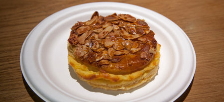 Pantxineta displayed on white plate over wooden background. Typical dessert of the Basque Country