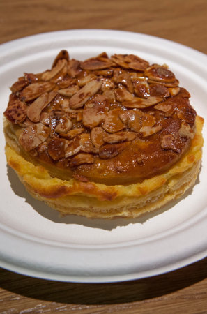 Pantxineta displayed on white plate over wooden background. Typical dessert of the Basque Country