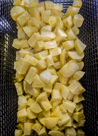 Basket of diced potatoes in the deep fryer of a restaurant kitchen. Overhead viewの写真素材