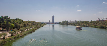 Canoes rowing beside fluvial tourist cruiser of Guadalquivir river, Seville, Andalusia, Spainの写真素材