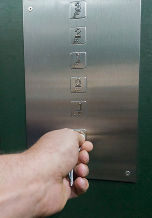 Mature man hand turning a key inside elevator. Restrict the use of elevator to specific floorsの写真素材