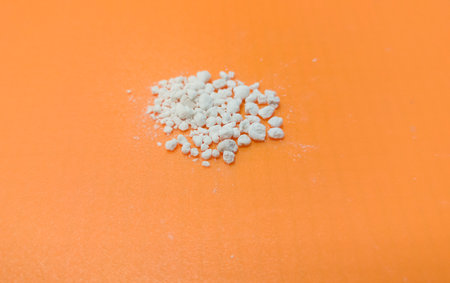 Perlite, lightweight material made from expanded volcanic glass. Handful of granular soil additive over orange backgroundの写真素材