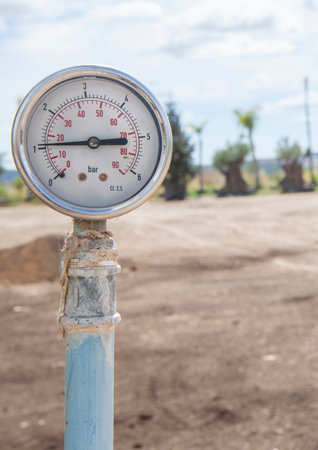 Irrigation system pressure gauge or manometer. Garden center greenhouses at bottomの写真素材