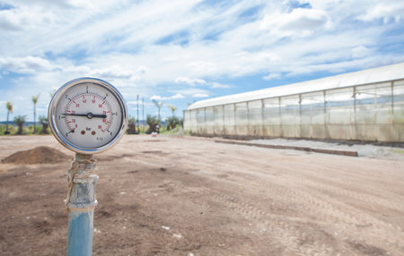 Irrigation system pressure gauge or manometer. Garden center greenhouses at bottomの写真素材