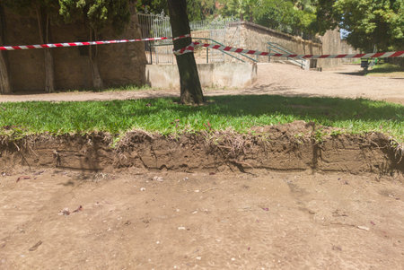 A trench dug in a public garden. The cut in topsoil is visible
