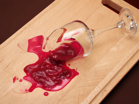 Broken wineglass on the table. Poured red wine, like blood.の写真素材