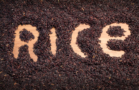 raw riceberry rice on wooden table with rice word symbol.jpgの写真素材
