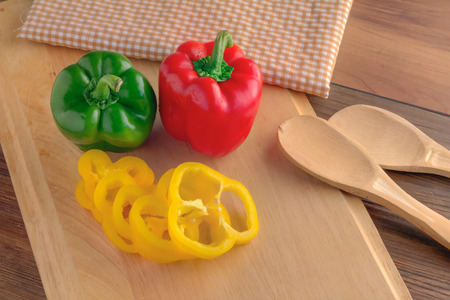 fresh sweet pepper on woodn board with wooden spoonの写真素材