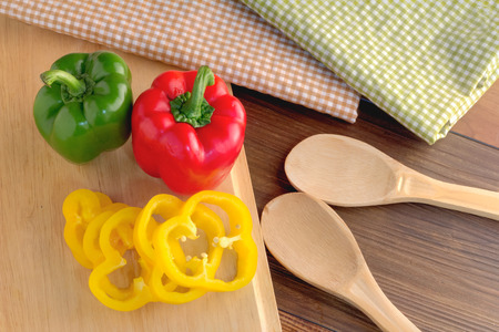 fresh sweet pepper on woodn board with wooden spoonの写真素材
