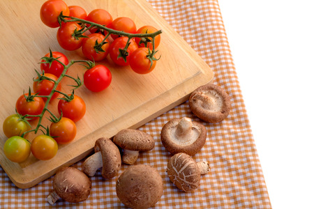fresh tomato and mushroom on wooden plate with brown fabric backgroundの写真素材