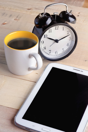 coffee cup with alarm clock and smart phone on the wooden floor vintage color conceptの写真素材