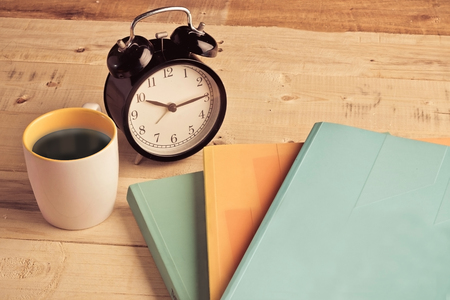 coffee cup with alarm clock and books on the wooden floor vintage color conceptの写真素材