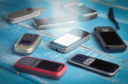 Mobile phones background. Pile of different smartphone with glow screen in the middleの写真素材