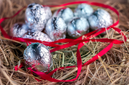 Chocolate eggs with silver foil hidden in the hay nest Easter conceptの写真素材