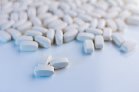 Pile of many white drug pills laying in a pile selective focusの写真素材