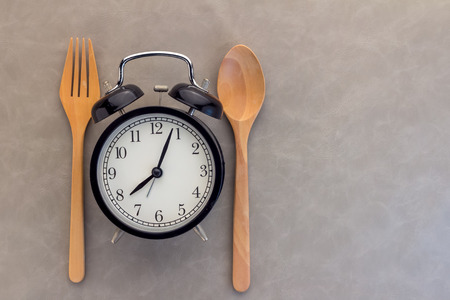 berakfast time concept  alarm clock with wooden spoon and fork