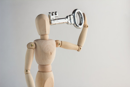 wood man holding key on white backgroundの写真素材