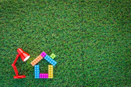 home model with red lamp on green grass texture background with copy-space for your textの写真素材