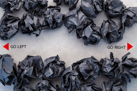 black crumpled paper ball with left right direction on grey leather background business concept.jpg