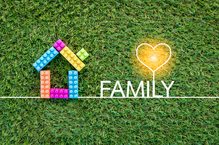 family concept with house toy on green grass texture background.jpgの写真素材