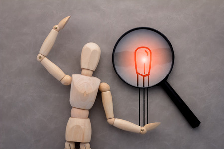 wooden figure and drawing of match and magnify on grey background.jpgの写真素材