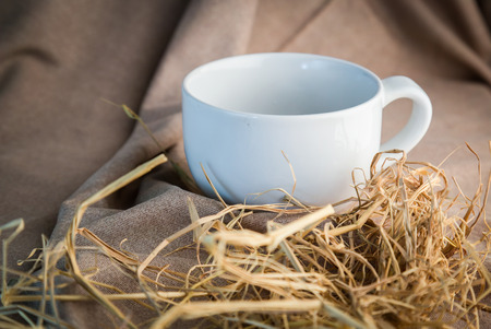 white Ceramic glass and dry hay on beige plaid Tableclothの写真素材