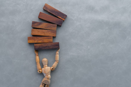 wooden man make a building with wood blocks on grey backgroundの写真素材