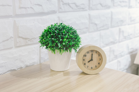 flowers and alarm clock on a wooden table and white stone wallの写真素材