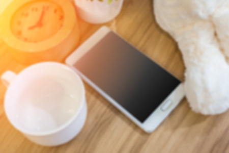 Smart phone, alarm clock and coffee cup on wooden table backgroundの写真素材