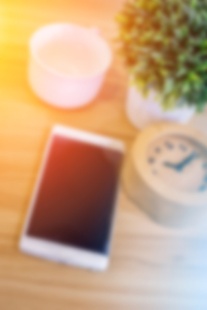 Smart phone, alarm clock and coffee cup on wooden backgroundの写真素材