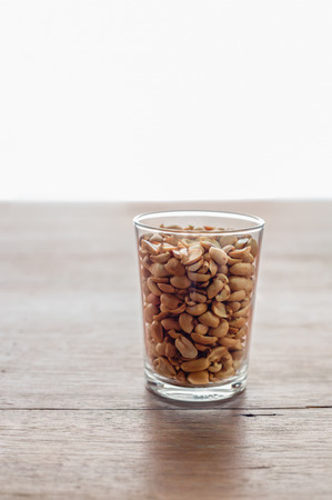 Peanuts soybean on glass cup  on a white background and wooden table topの写真素材