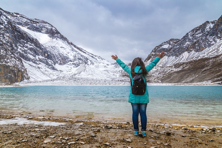 girl tourist standing alone by the mountain landscape during summer vacation with his backpack back viewの写真素材