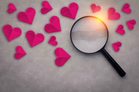 red heart paper with magnifying glass on gray leather backgroundの写真素材