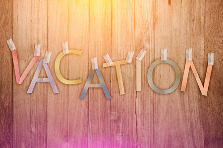 vacation text paper cut stick on wood plank texture background.jpgの写真素材