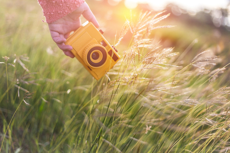 girl hand holding retro photo camera outdoor hipster Lifestyle with sunset lights on background film colorsの写真素材