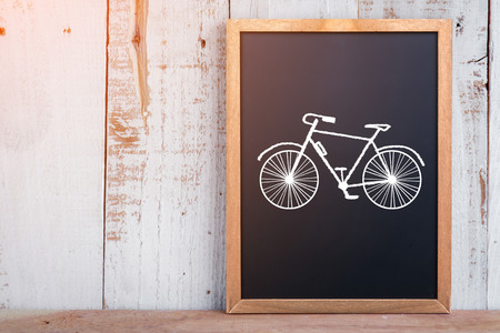 hand drawn bicycle on chalkboard with free copy space on rustic wooden plank creativity ideas conceptの写真素材