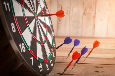Red dart arrow hitting in the target center of dartboard business success ideas concept