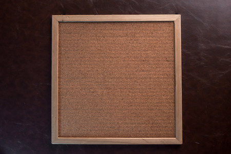 blank corkboard / bulletin board with a wooden frame on leather backgroundの写真素材