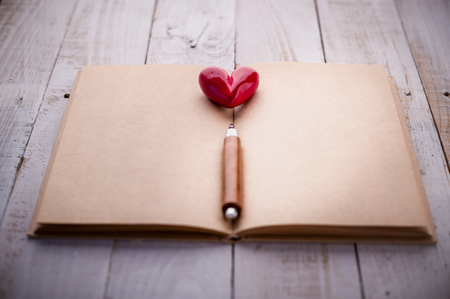 red heart object with wooden pencil on blank page notebook with free copy space for your text love ideas conceptの写真素材