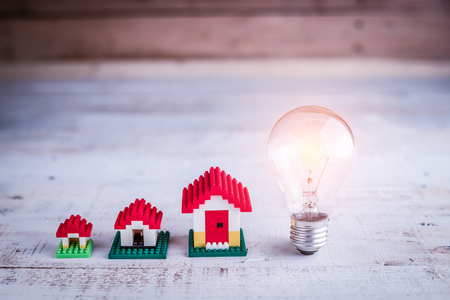 light bulb with house model on wooden floor house ideas conceptの写真素材