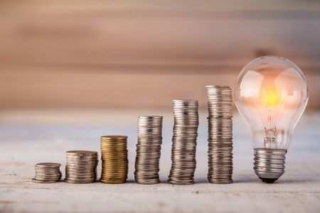 Glowing light bulb with heap coins stair business conceptの写真素材